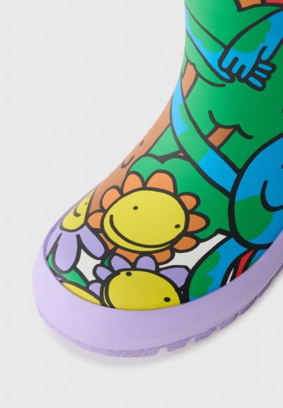 Fargerik gummistøvel med et livlig blomsterdesign, inkludert smilende blomster, lilla såle og en blank overflate. Moro, lekent estetikk.