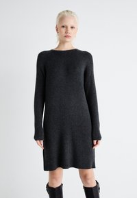 Robe en tricot côtelé gris foncé avec des manches longues, un col rond et une coupe ample, arrivant au mi-cuisse. Tissu texturé avec une légère élasticité.