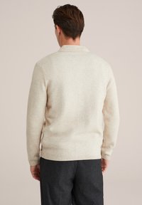 Pulover din tricot crem cu guler, mâneci lungi și manșete cu model. Prezintă un finisaj texturat și o croială ușor ajustată.