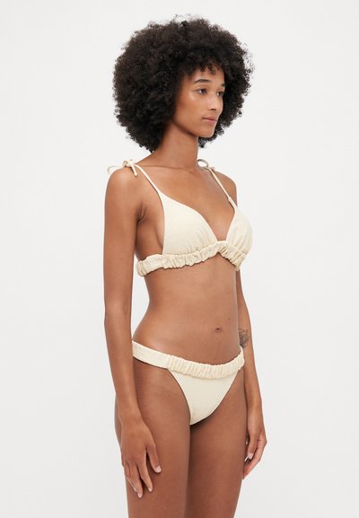 Cremfarbener Bikini mit strukturiertem Stoff, bestehend aus einem Triangel-Oberteil mit verstellbaren Bändern und Rüschenakzenten am Höschen.