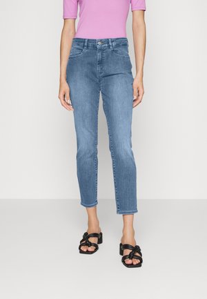 Jeans de mezclilla azul claro con un diseño ajustado, cintura de altura media y longitud cropped. Combinados con una blusa rosa de manga corta y sandalias negras.