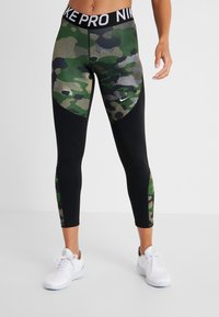 Leggings Nike Pro con un diseño ajustado, que presentan un patrón de camuflaje verde en la parte frontal, laterales negros y una cinturilla ancha con marca.