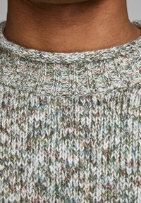 Gestrickter Pullover mit einer strukturierten grünen Basis, die mehrfarbige Sprenkel aufweist. Gerippter Kragen und Muster verleihen ein gemütliches Aussehen.