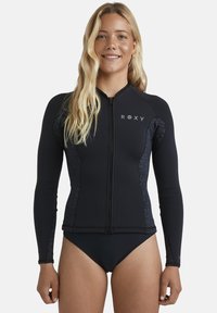 Czarny neoprenowy rash guard z długimi rękawami, zamek błyskawiczny z przodu oraz logo Roxy. Teksturowane akcenty po bokach w ciemnym wzorze.