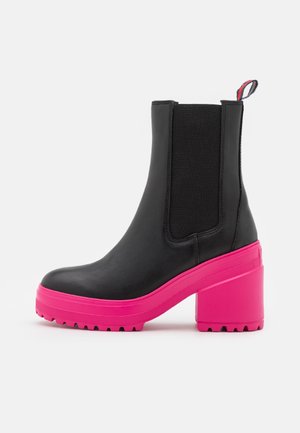 Schwarze Stiefelette mit auffälliger, knallpinker Plateausohle und Blockabsatz, elastischem Seiteneinsatz und kleinem Zugband hinten.