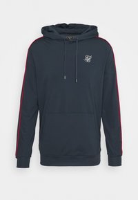 Mörkblå hoodie med röda sidostreck, en känguruficka och justerbar huva. Har en liten logotyp på bröstet. Mjuk textur, avslappnad passform.