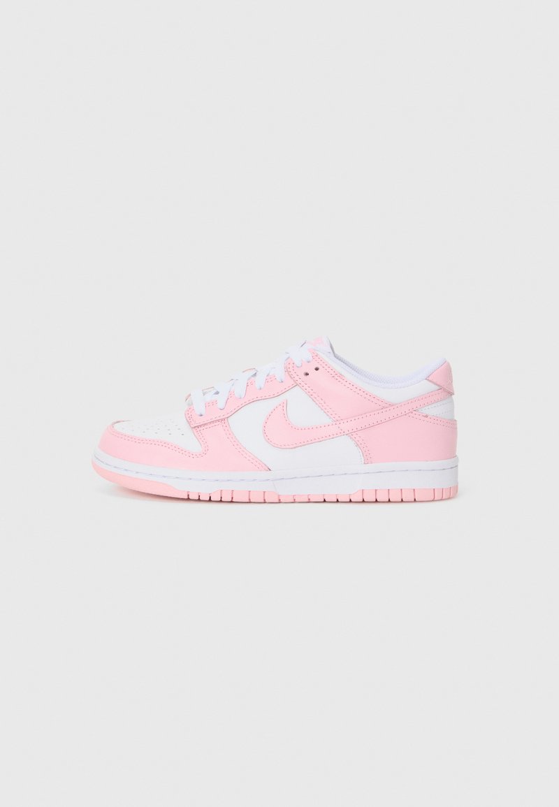 Vaaleanpunaiset Nike-tennarit, joissa on valkoisia yksityiskohtia. Kenkien päällinen on sileää nahkaa, kärjessä on reikäkiila ja pohjassa on vaaleanpunaisia tanttikkaita.