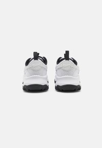 Nike sneakers featuring a white mesh upper, black accents, and textured rubber outsole with a heel pull tab for easy wear.