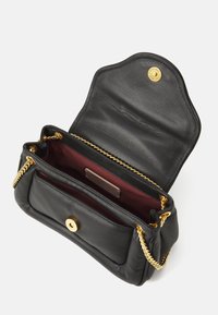 Sac en cuir noir avec une chaîne dorée, doté d'un intérieur bordeaux, d'une fermeture à pression magnétique et d'un design de rabat arrondi.