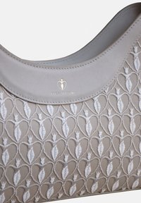Helle graue Handtasche mit gestickten weißen Herzmustern, glattem Lederbesatz und dezentem Markenzeichen auf der Vorderseite.