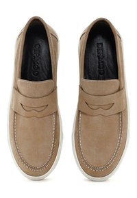 Zapatos de ante en tonos marrones con detalles de costura sutil, puntera redondeada y suela de goma blanca. Marca visible en el interior del zapato.
