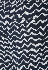 Marinblå och vit zigzag-mönstrad tyg med en strukturerad yta, som har en bakficka med en rak kant upptill.