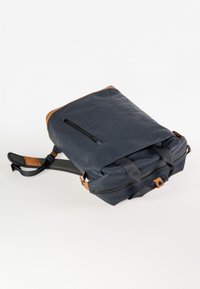 Marineblauer Rucksack mit braunen Lederbesätzen, schwarzen Riemen, vordere Reißverschlusstasche und zwei oberen Griffen auf weißem Hintergrund.