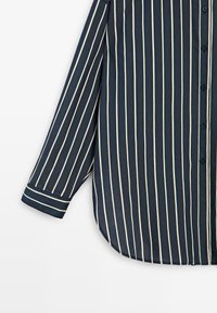 Marineblaues Langarmhemd mit weißen vertikalen Streifen, Knopfleiste vorne, abgerundetem Saum und kontrastierenden gestreiften Manschetten.