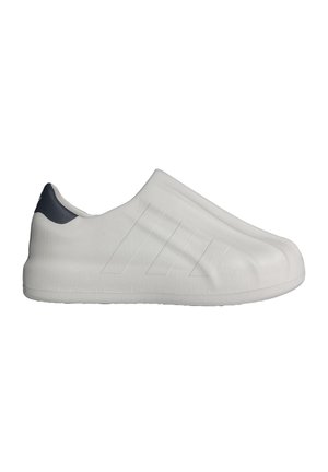 Minimalist white slip-on shoe with subtle ribbed texture and three faint stripes on the side, featuring a black heel tab.