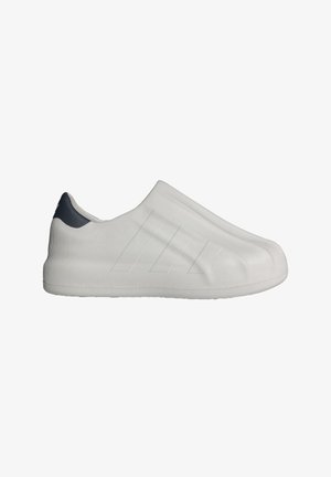 Chaussure blanche minimaliste à enfiler avec une texture subtile côtelée et trois fines rayures sur le côté, dotée d'une languette de talon noire.