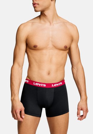 Male torso wearing black boxer briefs with a red Levi's branded waistband, standing against a white background.