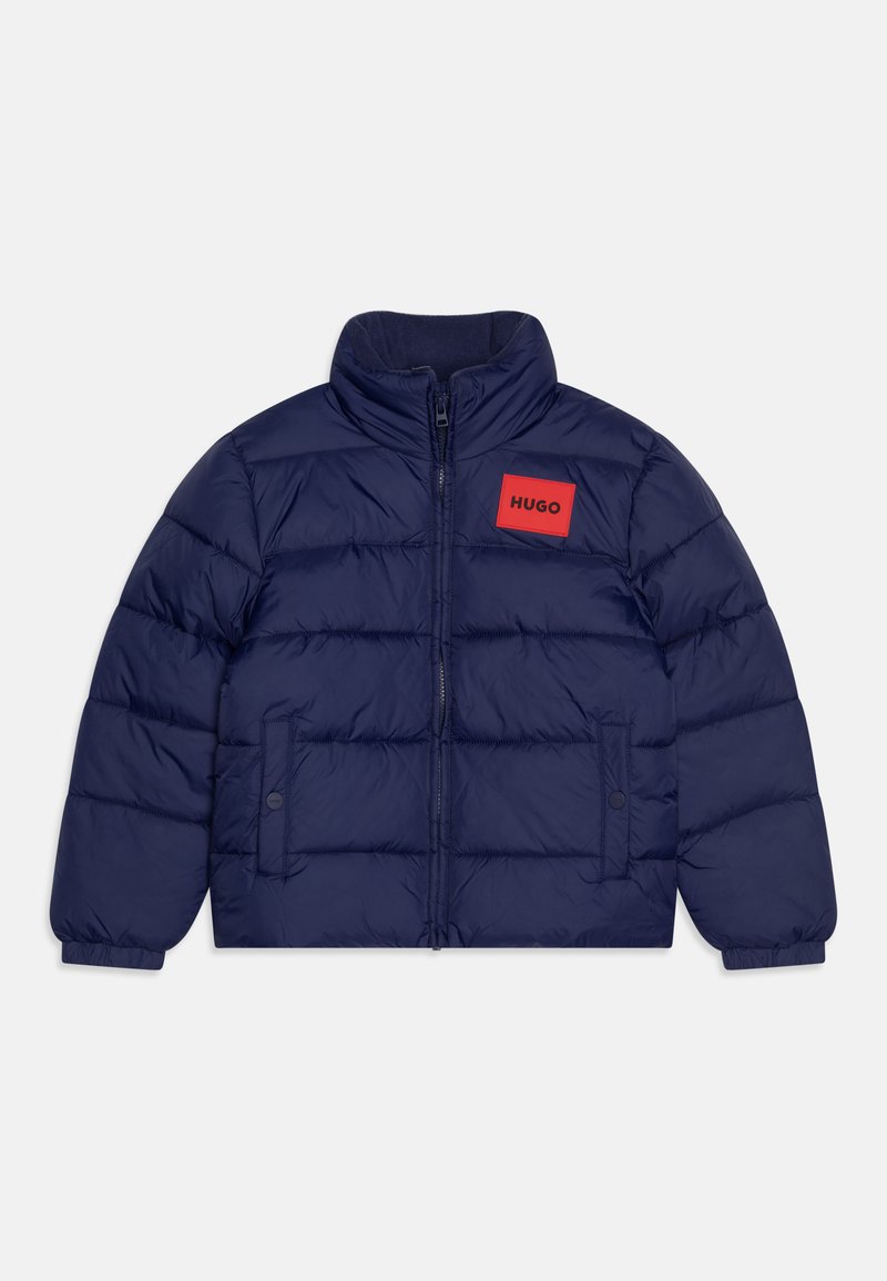 Veste matelassée bleu marine avec col haut, fermeture éclair avant et un patch logo carré rouge portant l'inscription "HUGO" sur la poitrine. Dotée de poignets élastiques.