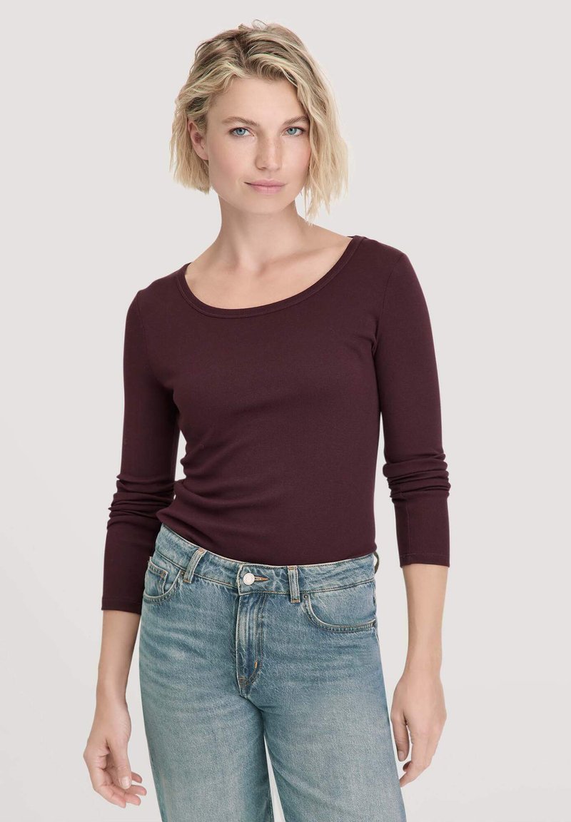 Bordeauxrood longsleeve shirt met een ronde halslijn, gecombineerd met lichtblauwe, high-waisted denim jeans; gladde textuur en aansluitend ontwerp.