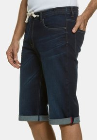 Shorts de mezclilla oscuros con un ajuste entallado, dobladillos enrollados, costuras en contraste, bolsillos frontales y una cintura con cordón.