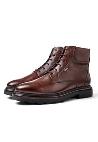 Brown leather ankle boots with a smooth finish, lace-up design, round toe, and rugged black rubber sole. Notable stitching detail.