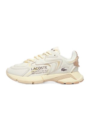 Creamfarvet Lacoste-sneaker med beige accenter, snørelukning, tekstureret sål, Lacoste-logo og geografiske koordinater trykt på siden.
