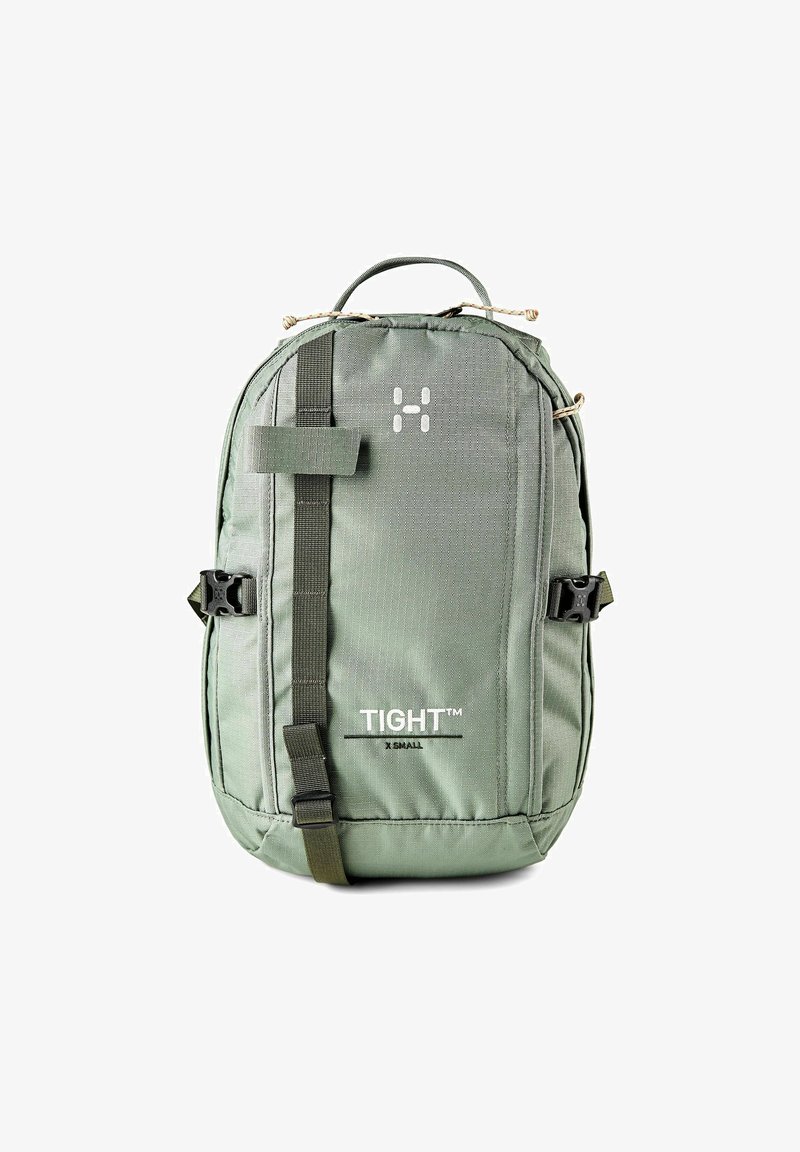 Kompakter grüner Rucksack mit vorderem Gurt, seitlichen Schnallen, Tragegriff oben und der Aufschrift "TIGHT X SMALL" auf dem Vorderpaneel.