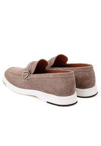 Graue Wildleder-Loafer mit einer weißen Gummisohle, runder Form und einem dekorativen Riemen mit einem Metallakzent.