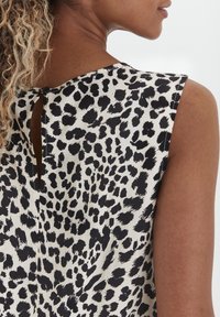 Black and white leopard print top featuring a keyhole back closure, sleeveless design, and smooth fabric texture.