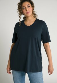 T-shirt V-nek di un blu scuro, con maniche corte, realizzato in un tessuto morbido. Vestibilità ampia e texture liscia, abbinato a jeans azzurri.