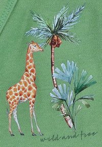 Een giraffe staat naast een palmboom en groene bladeren op een groene, gestructureerde stof achtergrond met de tekst "wild en vrij".