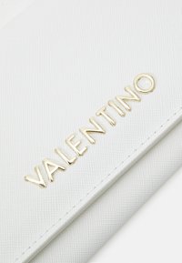 White textured wallet featuring embossed "VALENTINO" logo in gold, with a sleek design and clean lines.