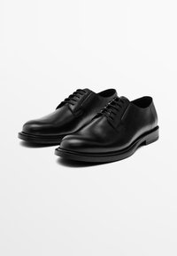 Pair of polished black leather men's dress shoes with laces, rounded toes, and low heels on a white background.