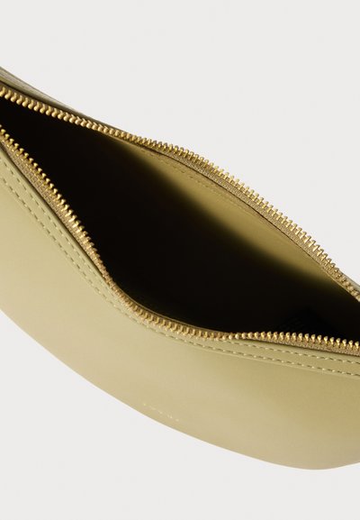 Clutch bag in pelle giallo-verde con zip dorata, caratterizzata da una texture liscia e una forma curvata, parzialmente aperta per rivelare il suo interno.