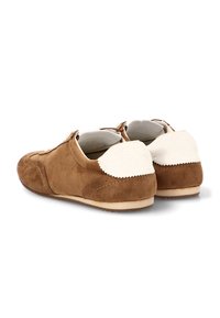 Zapatos de ante marrón con un acento color crema en el talón, con una forma redondeada y un detalle de costura mínima en los laterales.