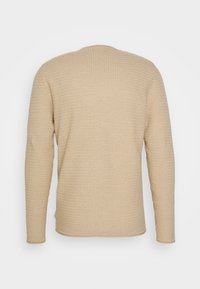 Beige langærmet sweater med et struktureret, vaffelmønster. Rundt udsnit ved halsen og ribbede manchetter. Glat stof, afslappet design.