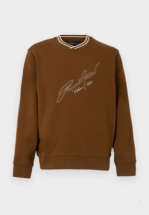 Smeđa duks s dugim rukavima s bijelim prugastim rebrastim ovratnikom i bijelim rukopisnim tekstom "Giorgio Armani Milano 1981" na prsima.