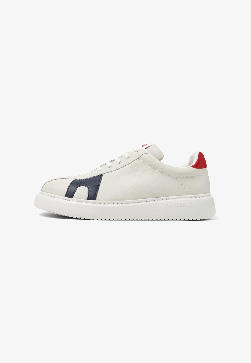 Low-top white sneaker with navy blue side detail, red heel accent, lace-up closure, and thick white rubber sole.