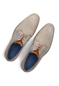 Beige canvas schoenen met bruin leren accenten, ronde neus en vetersluiting. Het interieur heeft een donkerblauwe voering met de merknaam.