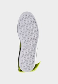 Semelle de chaussure avec une surface en caoutchouc blanc texturé arborant un motif d'étoile ; accents vibrants jaune et noir sur les bords.