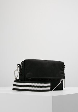 Czarna prostokątna torba na ramię z srebrnym zamkiem błyskawicznym i czarno-białym, odpinanym paskiem w paski, na białej powierzchni.