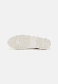 Suela de zapato de goma blanca con superficie texturizada, que presenta un patrón de concha y el nombre de la marca "JOOR" en relieve en la esquina inferior derecha.