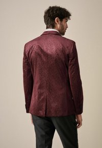 Sacou burgundy cu un model geometric, realizat dintr-un material neted. Dotat cu un sistem de ventilație unic, butoni negri și detalii de guler alb în contrast.