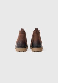 Hnědé kožené kotníkové boty s hladkou texturou, vybavené odolnou gumovou podrážkou, poutkem a kontrastním šitím.
