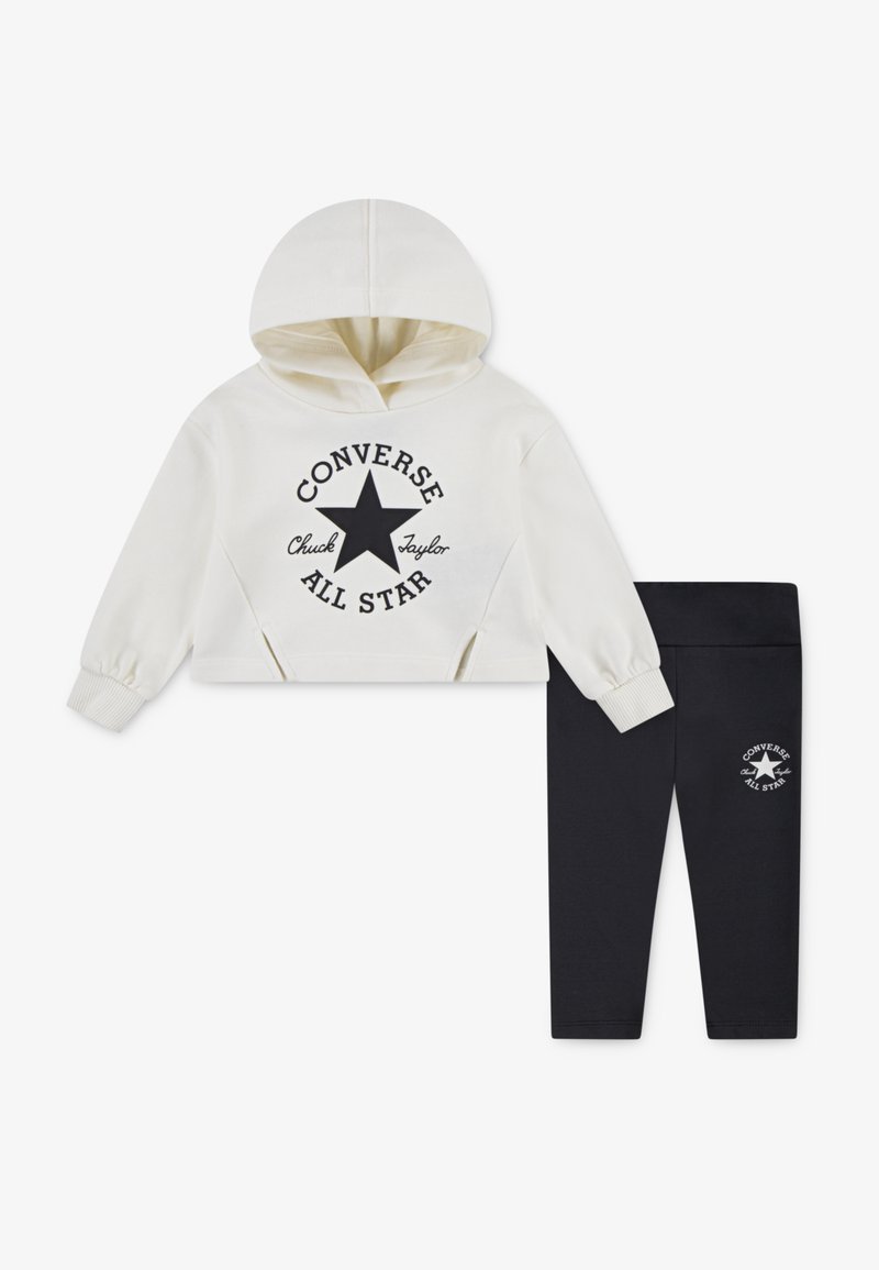Hvit kort t-skjorte med svart trykt stjernelogo og tekst, sammen med svarte leggings med en liten logo. Laget av bomullsblanding.