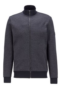 Grå zip-up jacka med hög krage, i ett texturerat tyg, med ribbade ärmslut och midja. Litet logotypmärke på vänster ärm.