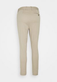 Beige kalhoty s úzkým střihem, vyrobené z hladké látky, s jednou zadní kapsou na knoflík a poutky na opasek.