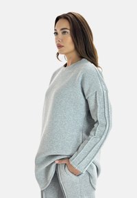 Grijze sweatshirt met een relaxte pasvorm, voorzien van lange mouwen en textuurstof. Zijkanten met strepen voegen detail toe aan het ontwerp.