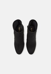 Stivaletti neri in suede, dal design elegante e aderente. Presentano una zip laterale e una superficie liscia con punta affusolata.