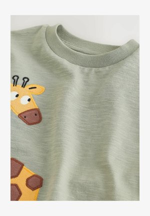 T-shirt en coton vert avec un dessin de girafe brodée en jaune et marron, doté d'un col côtelé et d'un tissu texturé.